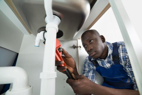 Man fixing pipes under sink